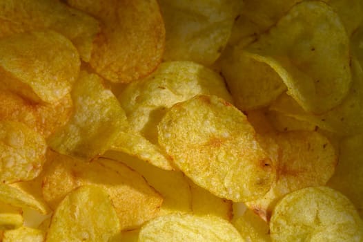 A vibrant collection of golden potato chips rests together, offering a tempting crunch for snack enthusiasts.