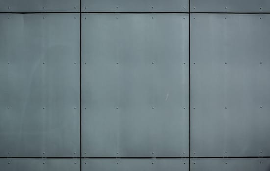 A smooth, industrial wall features large metal panels reflecting a contemporary design, showcasing urban elegance.