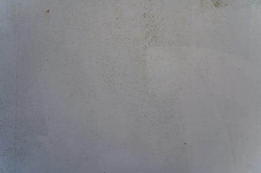 A textured wall displays a blend of muted colors and imperfections, capturing a serene, quiet atmosphere in daylight.