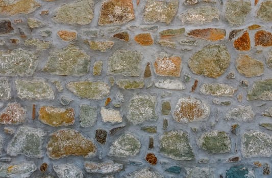 Intricate patterns emerge on a weathered stone wall, illuminated by the warm glow of sunset in a charming village.