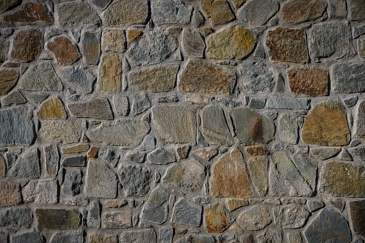 Natural stones blend in earthy tones create a rustic wall, showcasing textures and patterns unique to each stone.
