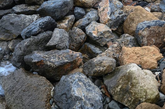 Colorful stones and pebbles create a textured carpet along the water's edge during a tranquil evening by the sea.