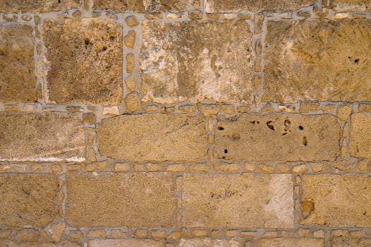 Ancient stone wall displays warm hues and textures, revealing the craftsmanship of a bygone era in sunlight.