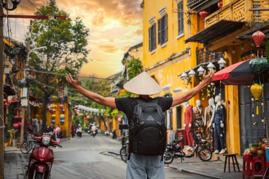Asian male traveler tourist in traditional vietnamese Non La hat on a street in old town in Hoi An city in Vietnam in Asia