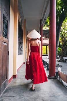 back of a Vietnamese tourist woman in Non La hat at a pagoda temple in Vietnam on a trip to Asia