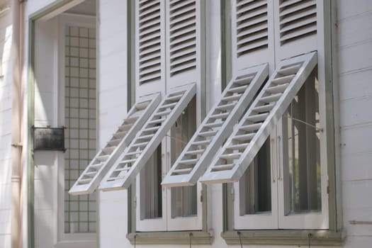 Two wooden shutters are open wide, showcasing the warm sunlight.