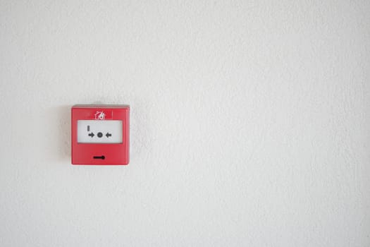 Red fire alarm panel is displayed on a plain white wall background.