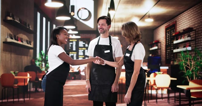 Chef shakes hands with diverse team at restaurant coffee shop.