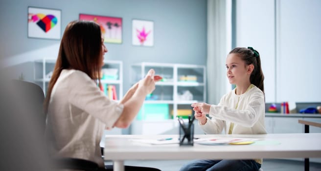Little girl learns sign language from hearing disability teacher. Healthcare profession.