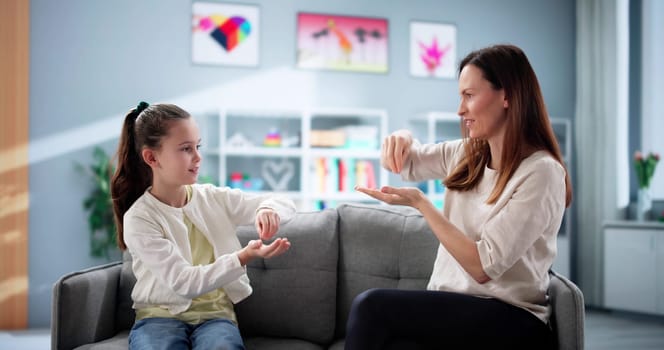 Young girl learns sign language from teacher to overcome hearing disability.