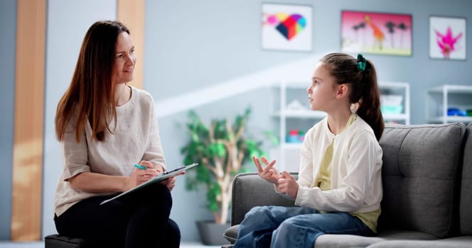 Caring therapist helps unhappy child overcome sadness during counseling session.