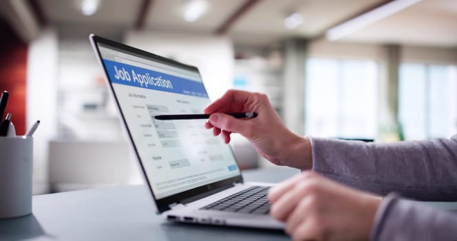 Young Woman Filling out Online Job Application on Office Laptop.