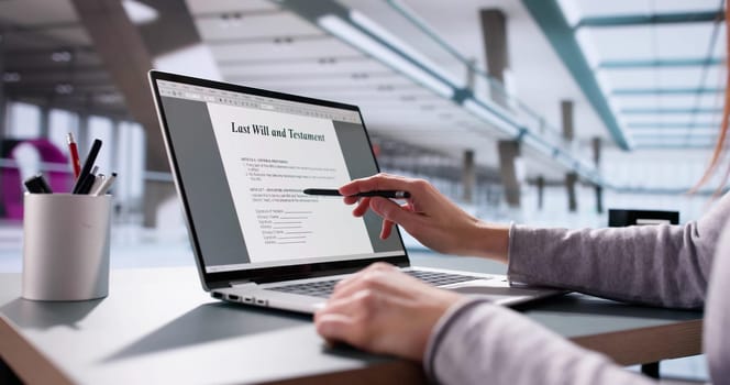 Person writing last will and testament, inheritance close-up, legal laptop.