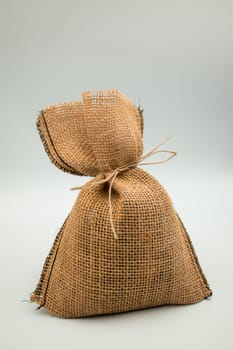Rustic burlap sack with string tie on neutral background.