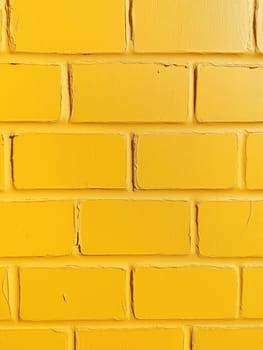 Close-up of a painted yellow brick wall. No people are present. The vibrant color and visible mortar lines create a textured surface.