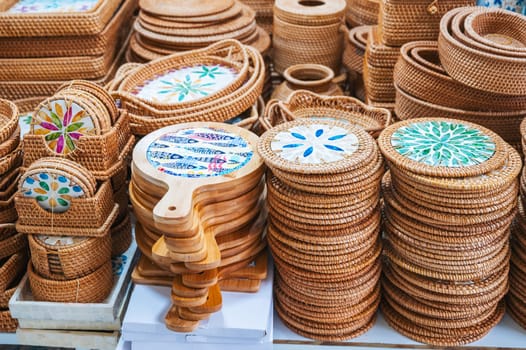 wicker baskets and containers and handmade wooden tableware on the counter at Asian market in Vietnam