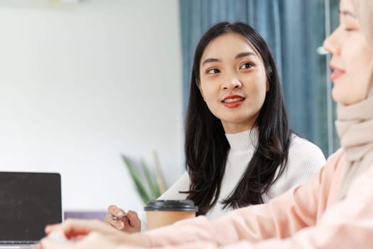 A young Asian woman actively participates in a meeting, demonstrating collaboration and engagement with colleagues.