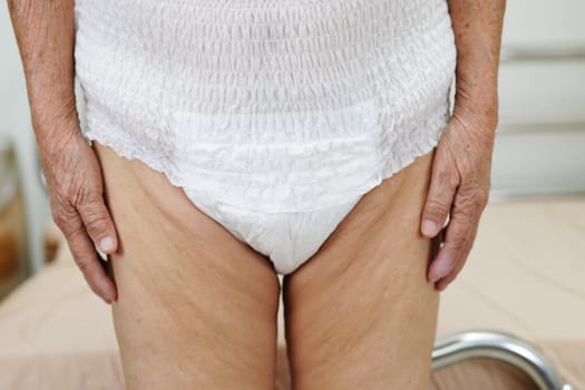 Asian elder senior woman patient wearing adult incontinence diaper pad in hospital.