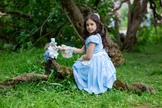 Young caucasian girl in blue dress playing with stuffed rabbit in enchanted forest.