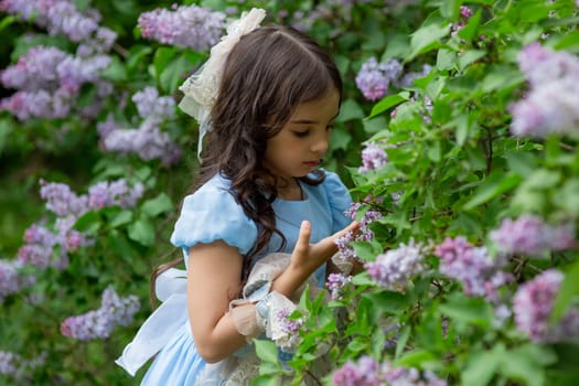 Young caucasian girl admiring lilac flowers in blooming garden.