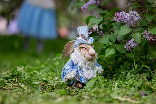 White rabbit in blue suit among lilac flowers in garden setting.
