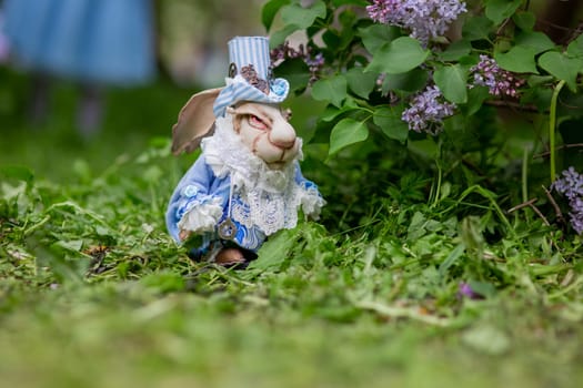 White rabbit in blue victorian outfit among lilac and greenery in a garden scene.