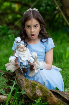 Surprised caucasian female child in blue dress holding rabbit toy in outdoor setting