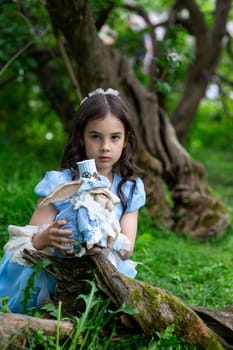 Young caucasian girl in blue dress holding rabbit doll in enchanted forest setting