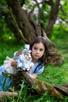 Young caucasian girl in blue dress holding rabbit toy in woodland setting