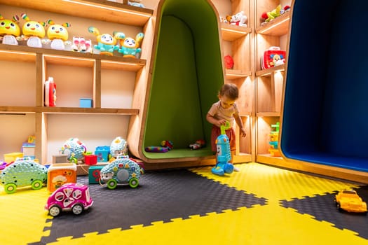 Child playing in colorful playroom with shelves full of toys and a fun interactive vacuum cleaner