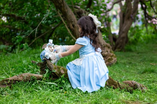 Young brunette girl in blue dress playing with toys in forest.