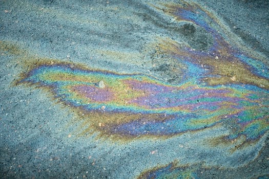 Gasoline or oil spill on asphalt creating rainbow colorful pattern.