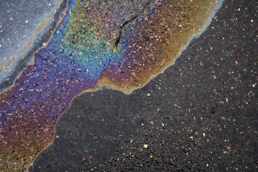An oil puddle on the wet pavement, drawing attention to the impact of pollution on the environment