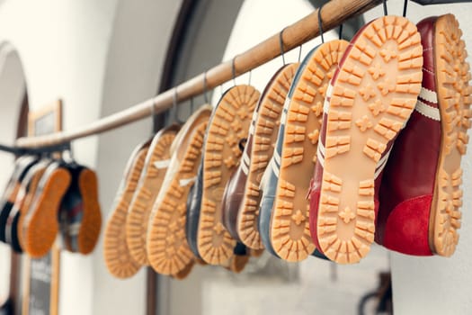 A collection of vintage sneakers with distinctive rubber soles hanging on a wooden rod in a European market. A perfect shot for fashion, retail, and lifestyle concepts.