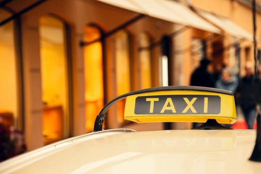 A close-up of a yellow taxi sign on a car roof, glowing against a blurred city background with warm lights. Ideal for transportation, travel, and urban lifestyle themes.