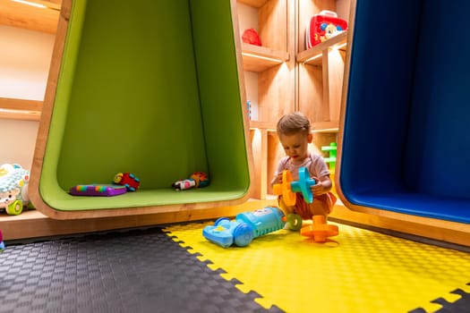 Toddler playing with activity toys and exploring a modern, colorful, and cozy indoor playroom