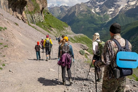 People with backpacks and scandinavian sticks climb the mountains in Caucasus