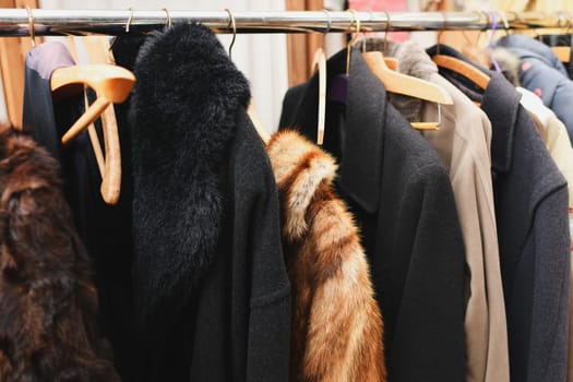 A vintage fur coat, a coat with a fur collar, a coat made of fox or rabbit fur hang on a hanger in a second-hand store.
