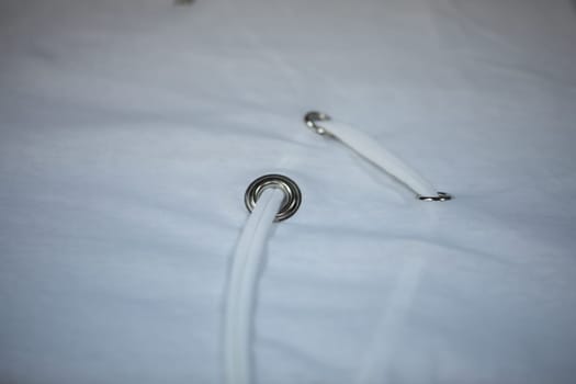 This is a detailed view of a grommet that features a white lace intricately threaded through it and around