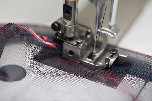 A closeup view of a sewing machine needle at work on a piece of vibrant and creatively textured fabric