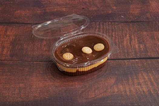 A dessert with a cookie on top of it. The dessert is in a plastic container