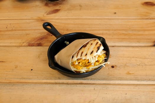 A pan of food with a wrap around it. The wrap is brown and the food is grilled