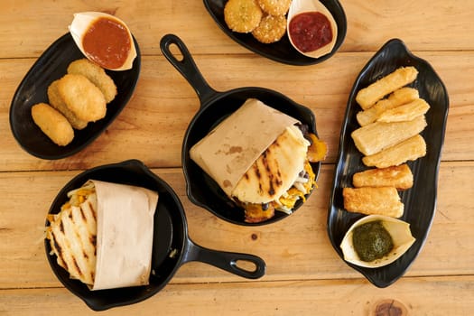 A table with a variety of food items including sandwiches, chips, and dips. Scene is casual and inviting, as it is a gathering or a party where people can enjoy a variety of food options