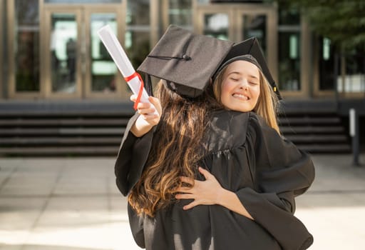 Two female graduates are hugging each other, celebrating their academic achievement