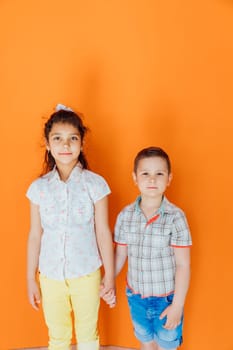 Boy And Little Girl Holding Hands On Orange