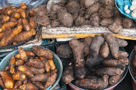 fresh yam and sweet potato tubers on counter at a street market in Asia