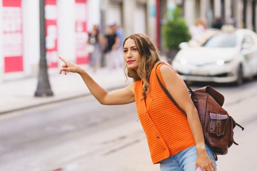 Latin beauty casual young woman calling taxi on city street