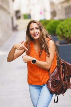 Vertical photo of a latin woman complaining about time pointing her wrist watch outdoors