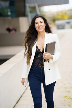 A confident, professional woman strides through an urban setting, carrying a clipboard that showcases her business skills and stylish flair, exuding poise and determination amidst the bustling city