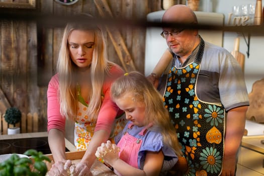 A warm, loving family happily enjoys quality time while cooking together delicious meals in their rustic kitchen